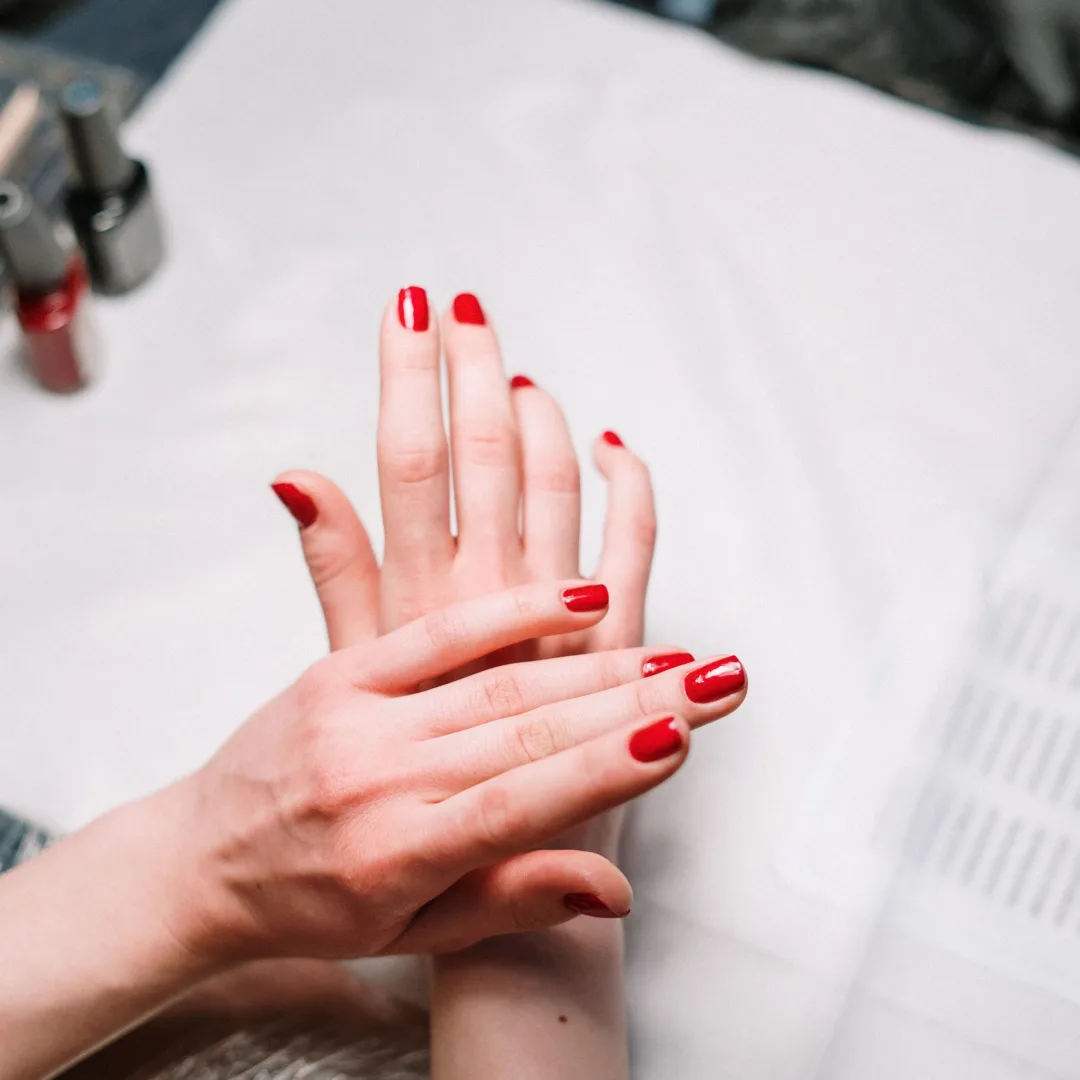 Professional hand treatment features a stylish red manicure at a modern nail salon.